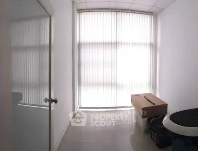 Bright room with large window and vertical blinds, ideal for office or study space.