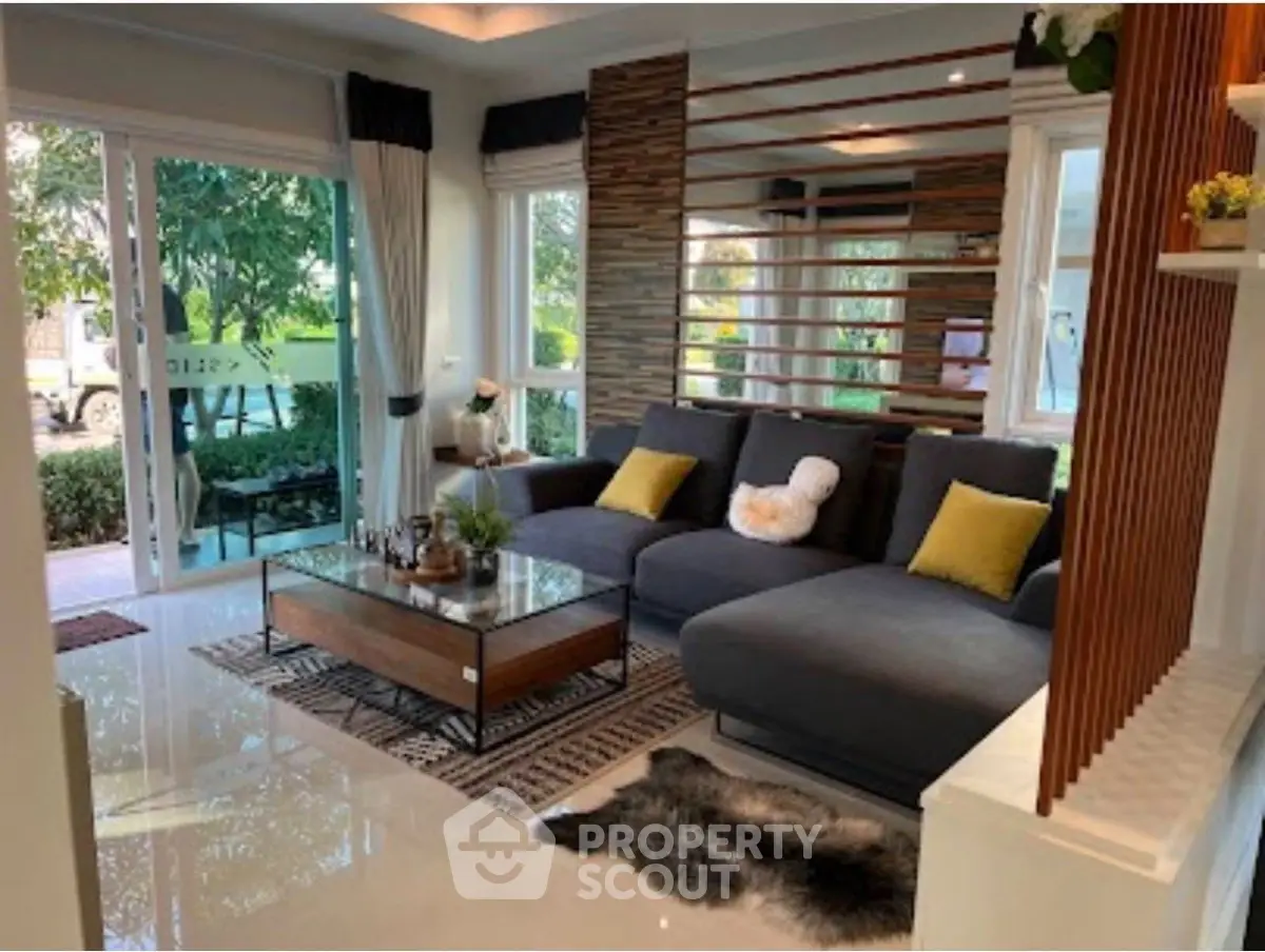 Spacious modern living room with large windows and stylish decor, perfect for relaxation and entertaining.