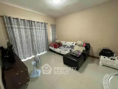 Cozy living room with sofa, fan, and curtains in a well-lit space.