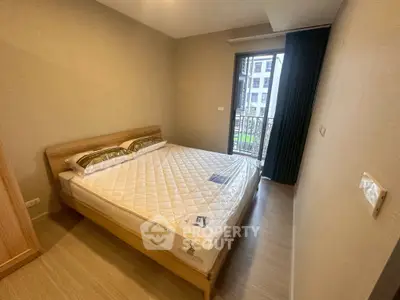 Cozy bedroom with a large window and balcony access in a modern apartment.