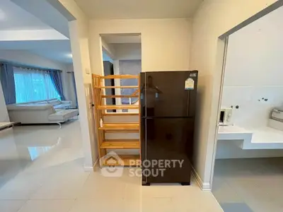 Spacious living area with modern fridge and elegant furniture, perfect for comfortable living.