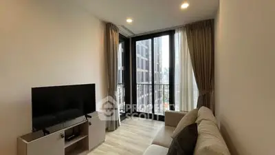 Modern living room with large windows and city view, featuring a sleek TV setup and cozy seating.