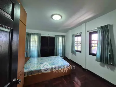 Spacious bedroom with natural light and wooden flooring