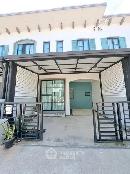Modern townhouse exterior with gated entrance and covered parking area.