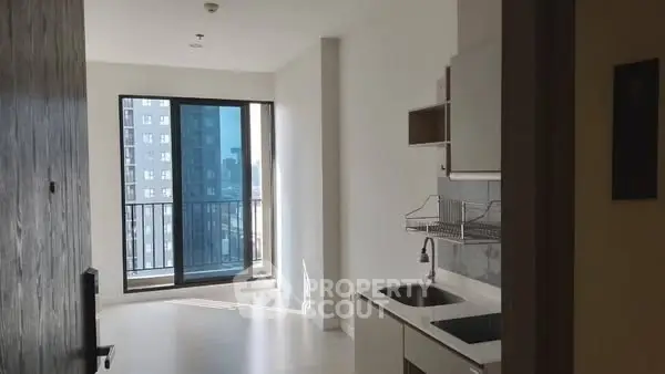 Modern apartment with sleek kitchen and balcony view in urban setting.