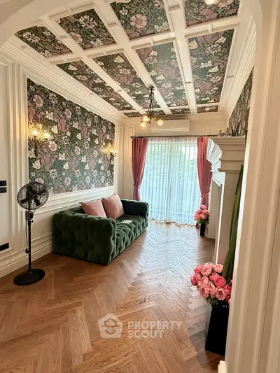Charming living room with floral wallpaper, elegant ceiling design, and cozy green sofa.