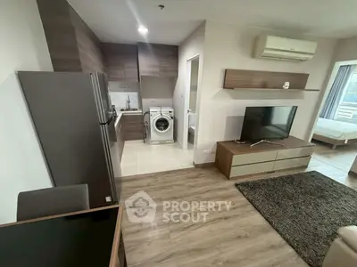 Modern living room with open kitchen and washing machine, featuring sleek furniture and wood flooring.