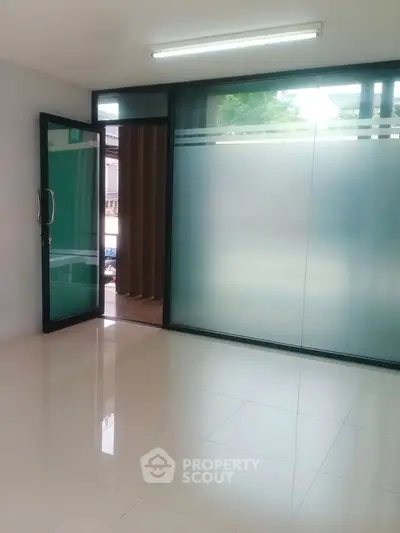 Spacious room with frosted glass doors and glossy tiled flooring, ideal for office or study space.