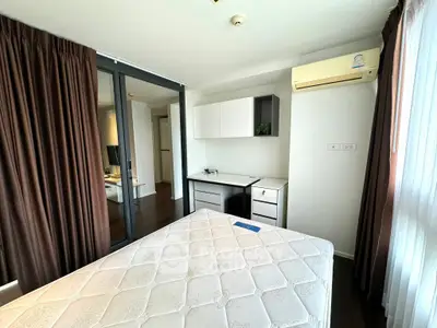 Spacious bedroom with modern furniture and large window for natural light.