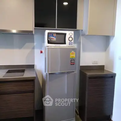 Modern kitchen with sleek cabinets and compact fridge in a stylish apartment.
