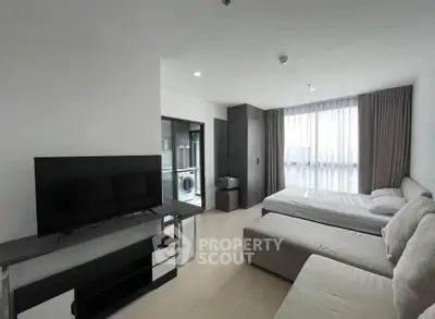 Modern studio apartment with sleek design, featuring a cozy living area, bed, and in-unit laundry facilities.