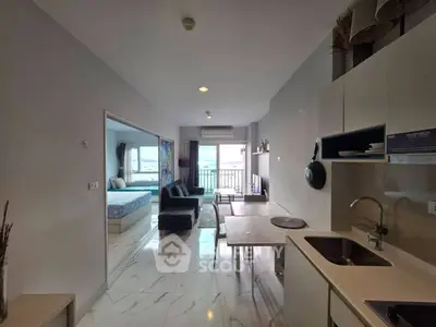 Modern open-plan apartment with sleek kitchen and spacious living area leading to a balcony with a view.