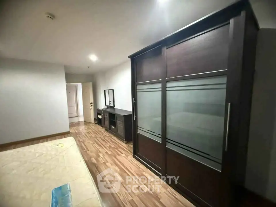 Spacious bedroom with wooden flooring and modern wardrobe