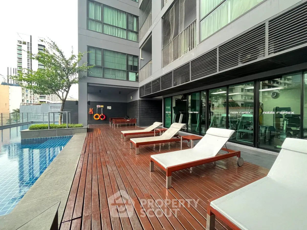 Modern apartment building with poolside lounge area and sleek design.