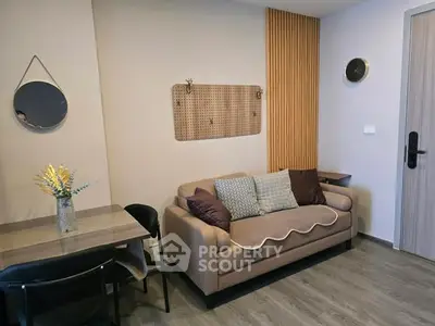 Cozy living room with modern decor, featuring a comfortable sofa, stylish wall accents, and a small dining area.