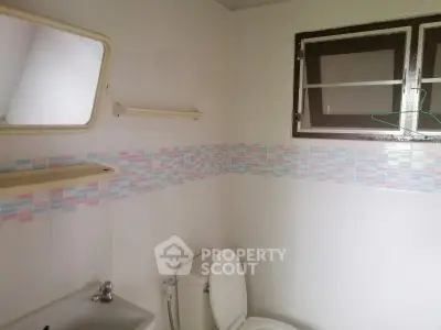 Cozy bathroom with pastel tile accents and natural light from window.