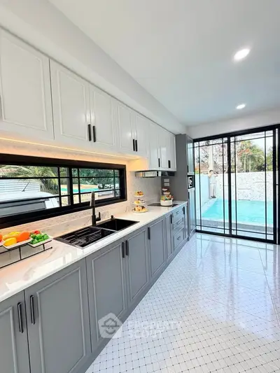 Modern kitchen with sleek cabinetry and pool view, featuring open layout and ample natural light.