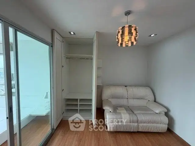 Cozy living room with modern lighting and sliding glass doors leading to a bright balcony.
