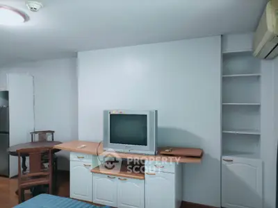 Cozy living room with vintage TV and built-in shelving, perfect for relaxation and entertainment.