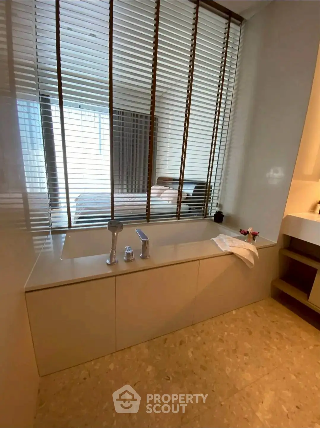 Modern bathroom with sleek bathtub and window blinds overlooking bedroom