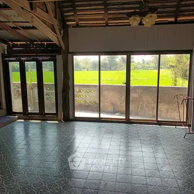 Charming rustic living room with large windows overlooking lush green fields, perfect for nature lovers.