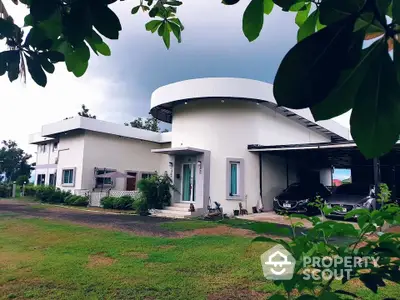 Modern circular house with lush garden and carport in serene setting