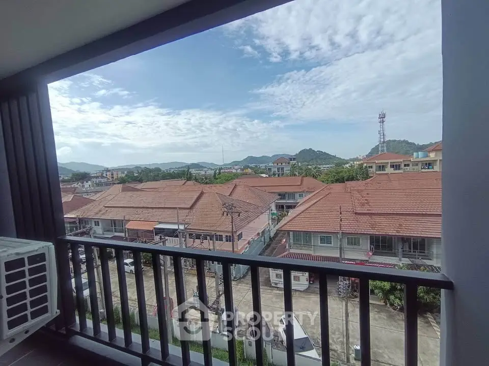 Stunning balcony view overlooking rooftops and scenic mountains, perfect for relaxation.