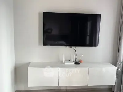 Modern living room with wall-mounted TV and sleek white cabinet
