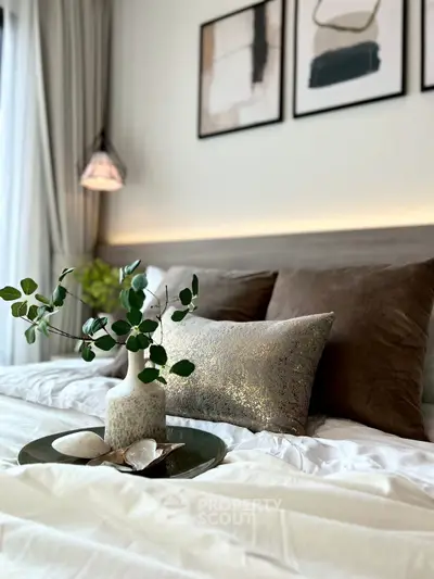 Elegant bedroom with stylish decor and cozy ambiance, featuring plush pillows and modern artwork.
