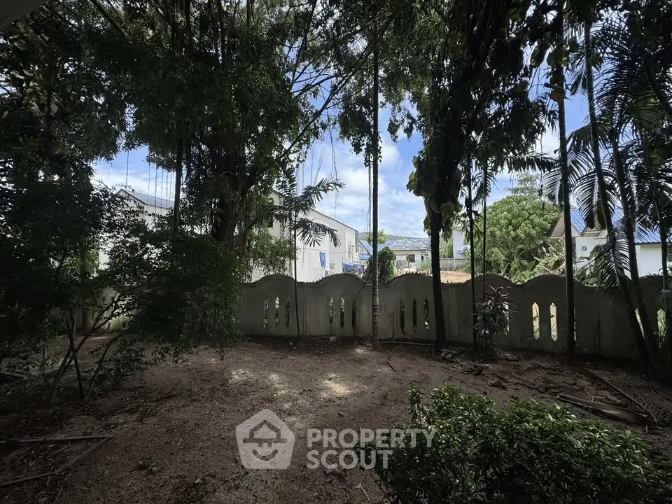 Spacious garden area with lush greenery and privacy fence, perfect for outdoor relaxation.