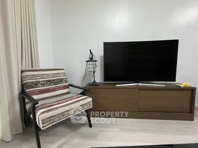 Modern living room with stylish armchair and flat-screen TV on wooden stand.