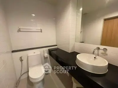 Modern bathroom with sleek black countertop and white fixtures in a contemporary apartment.