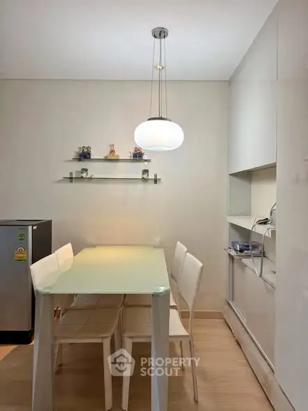 Modern dining area with sleek glass table and contemporary lighting in a stylish apartment.
