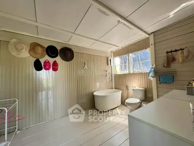 Charming rustic bathroom with hats on wall, standalone bathtub, and natural light.