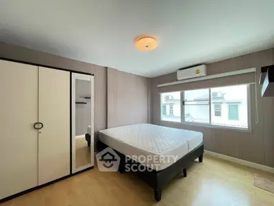 Spacious bedroom with large window and modern furnishings in a well-lit apartment.
