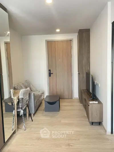 Modern apartment entrance with sleek wooden flooring and compact living area