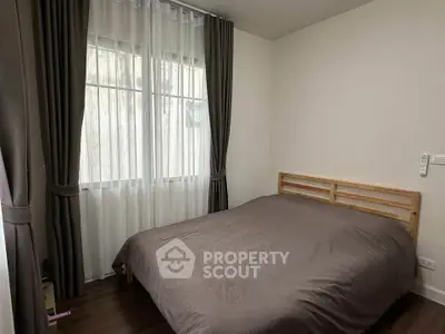 Cozy bedroom with wooden bed frame and large window with curtains