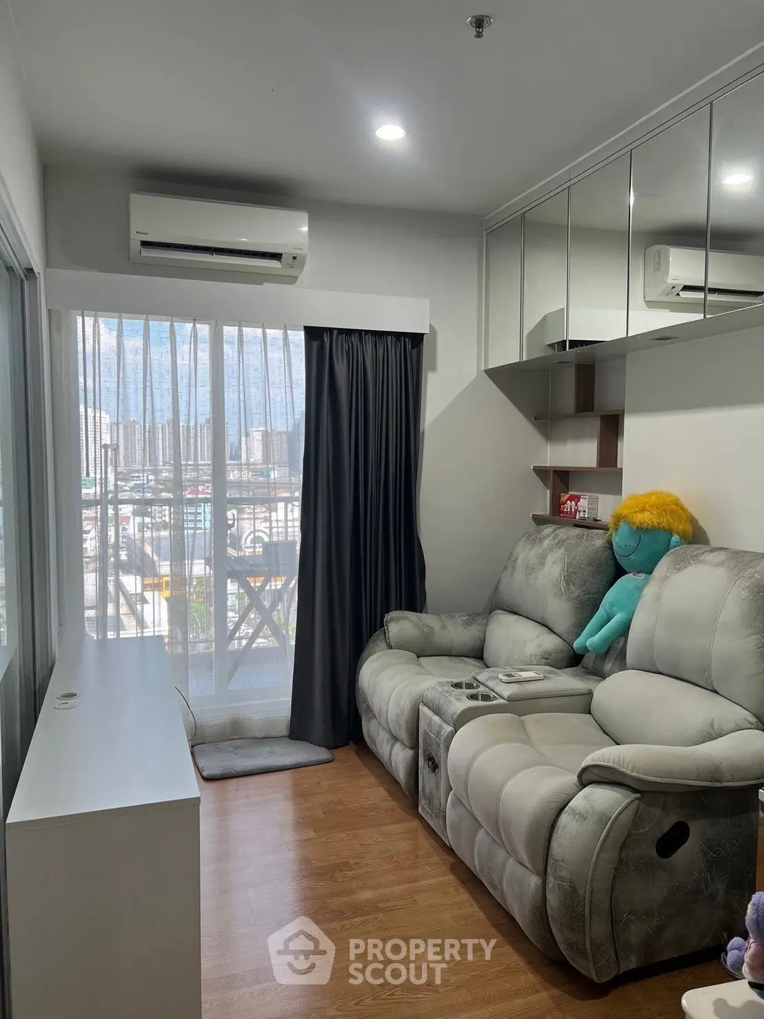 Cozy living room with plush sofa and city view from balcony, perfect for relaxation.