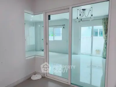 Spacious modern living room with glass doors and bright natural light.