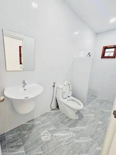 Modern bathroom with sleek design and tiled flooring, featuring a toilet and sink.