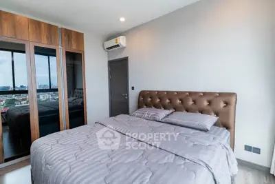 Modern bedroom with stylish decor and city view, featuring a plush bed and mirrored wardrobe.