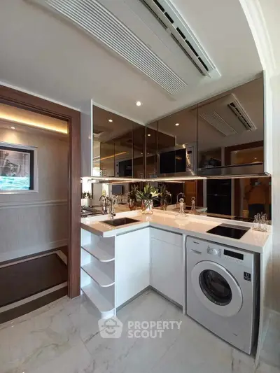 Modern kitchen with sleek design, featuring washing machine and induction cooktop.