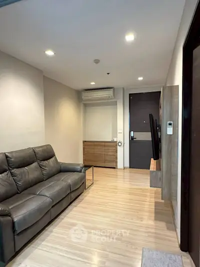 Modern living room with sleek leather sofa and wall-mounted TV in a cozy apartment.