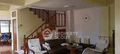 Charming living room with cozy seating and wooden staircase, perfect for relaxation.