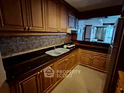 Charming kitchen with wooden cabinets and sleek black countertops in cozy apartment