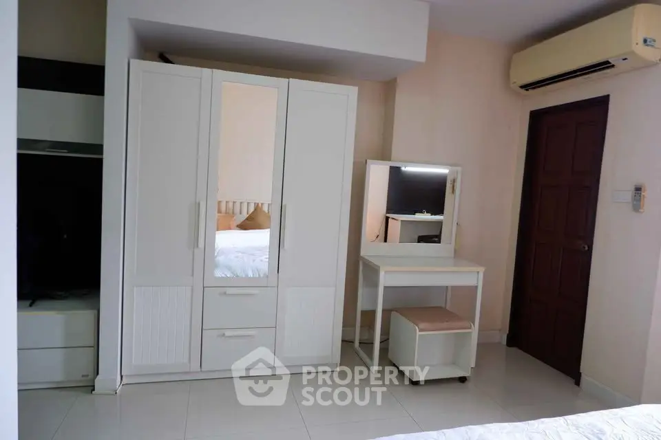 Cozy bedroom with modern white wardrobe and vanity set, featuring air conditioning for comfort.
