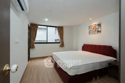 Spacious bedroom with modern decor and large window in a stylish apartment.