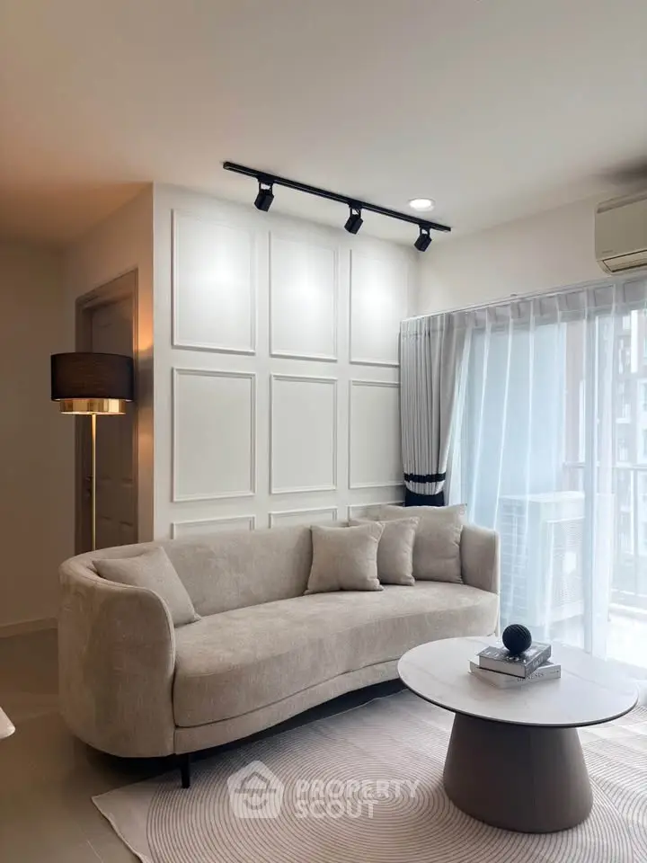 Modern living room with elegant beige sofa and chic coffee table, featuring stylish wall paneling and natural light.