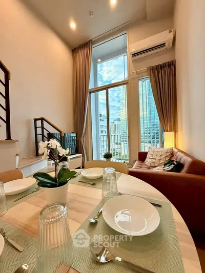 Modern living room with high ceilings and city view, featuring stylish decor and dining area.
