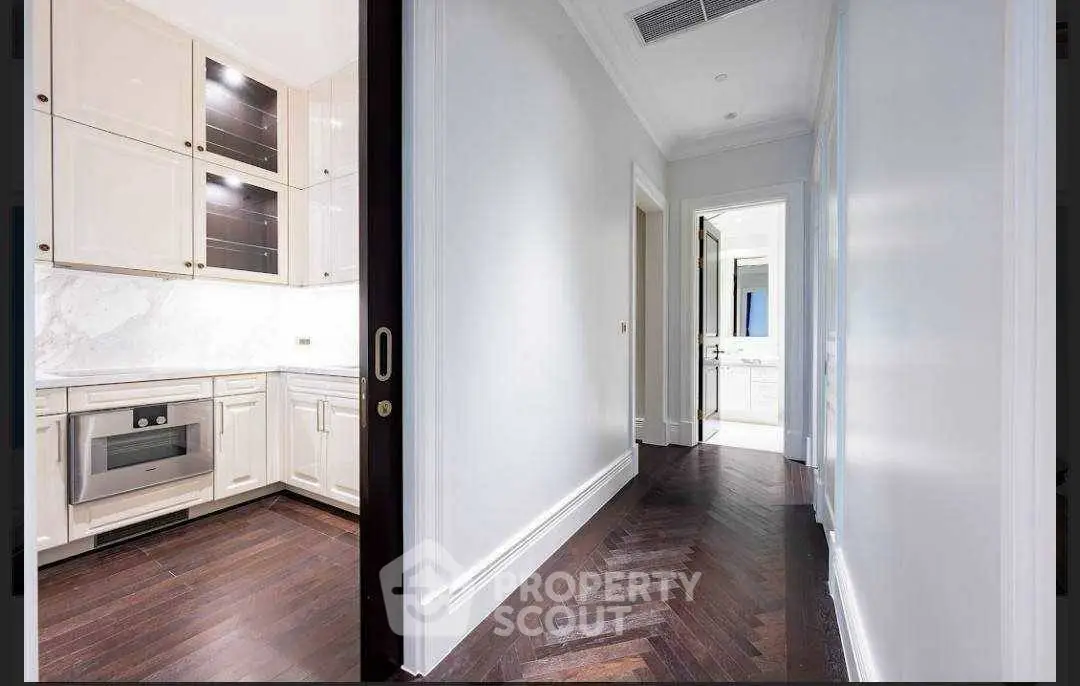 Luxurious hallway leading to a modern kitchen with elegant cabinetry and hardwood floors.